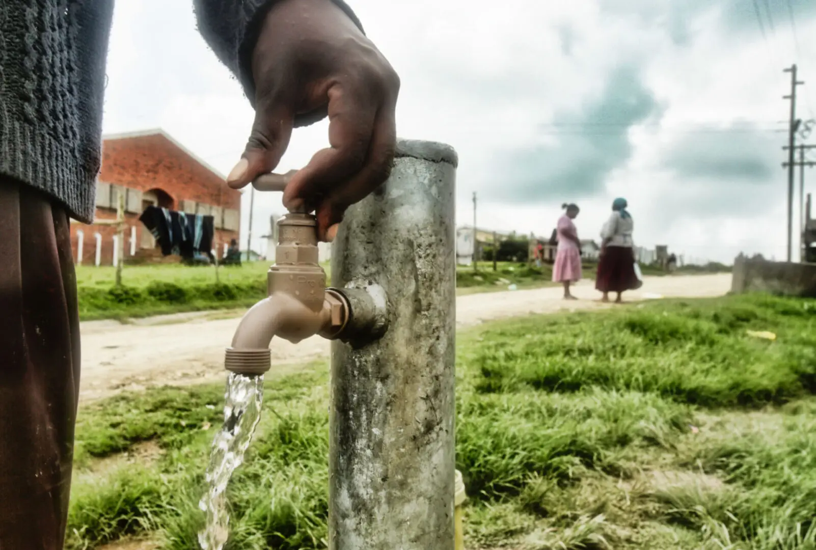 Hand turning on outdoor water faucet.