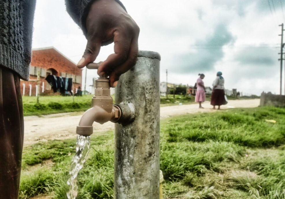 Hand turning on outdoor water faucet.